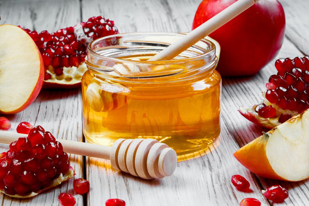 Jar With Honey, Apples And Pomegranates On White Wooden Background. Happy Rosh Hashanah. Traditional Symbols Of Jewish New Year Celebration.